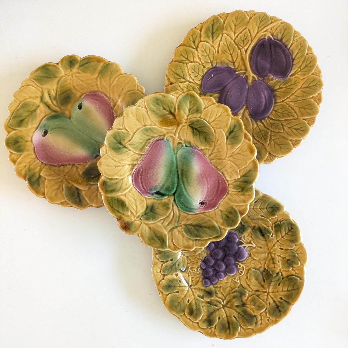 Assiette à dessert ancienne en majolique de Sarreguemines décor de prunes violettes en relief barbotine sur fond ocre jaune.