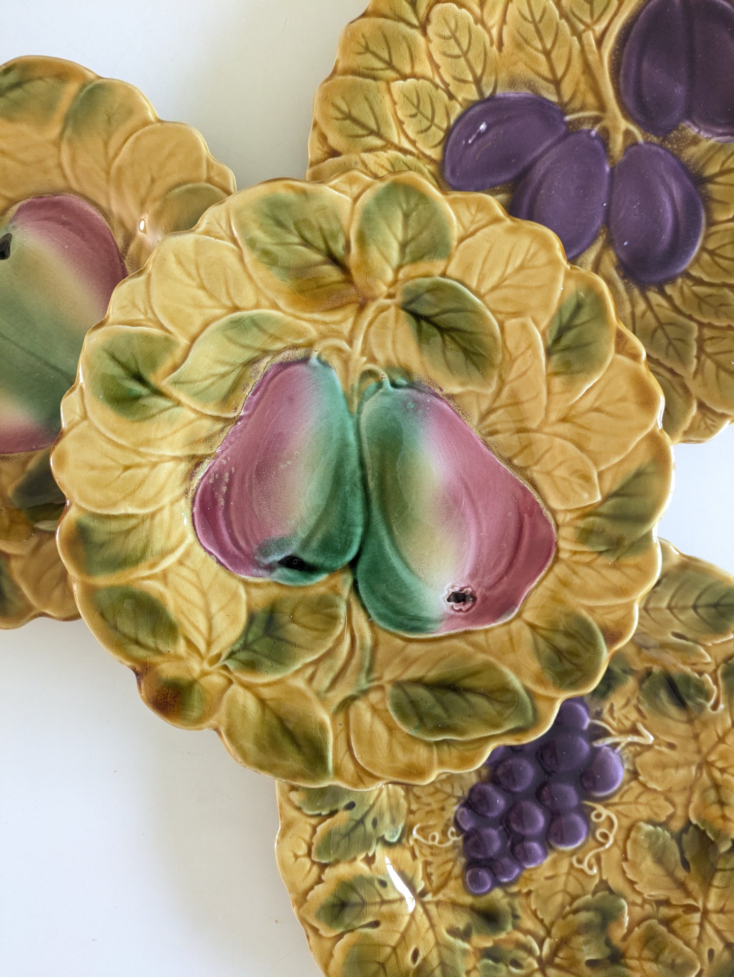 Détail de la barbotine Sarreguemines montrant le relief des poires et des feuilles de vigne, raisins,glaçure brillante et texture travaillée