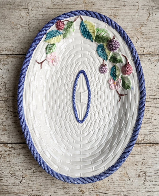 Grand plat de service ovale en barbotine vintage du Portugal, décor en trompe-l'œil de panier en osier tressé blanc, bordure torsadée bleue et relief de branches de mûres sauvages et fleurs roses.