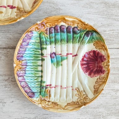 Vue détaillée du revers d'une assiette à asperges ancienne en barbotine Onnaing, montrant la glaçure crème, le pied de l'assiette, quatre points de cuisson et un fêle de vieillesse léger."